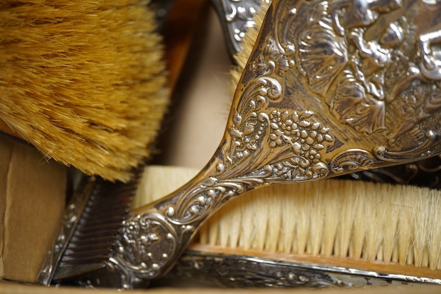 An Edwardian repousse silver mounted six piece dressing table mirror, brush and comb set, by Henry Matthews, Birmingham 1901, together with one other silver mounted hair brush and clothes brush.